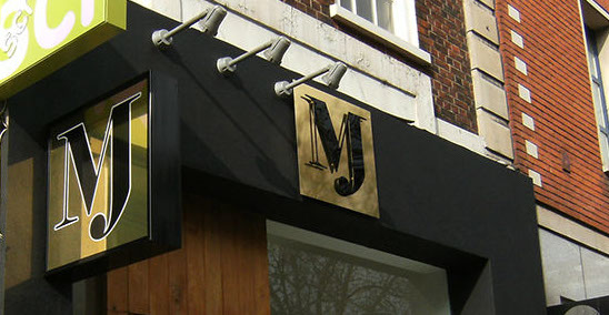 Mirror gold and black signage with protruding light box.